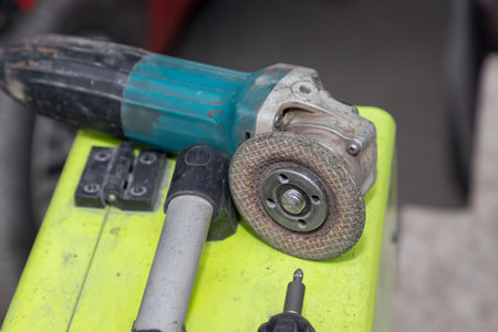 Used angle grinder with worn disc on a workbench â€“ heavy-duty power tool for cutting,...