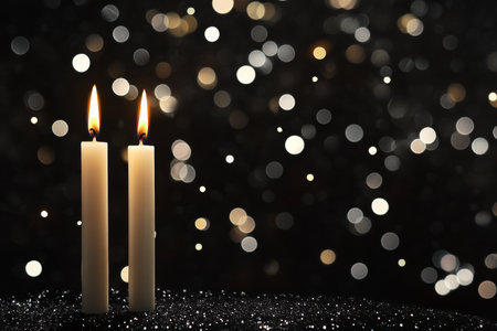 Elegant white candles against a black background with bokeh for holiday or wedding card designの写真素材