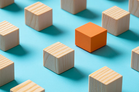 Close up view of wooden blocks and an orange cube on a blue background with soft shadows and bokehの写真素材
