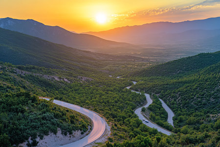 Stunning sunrise over mountain range with winding road and car in a minimalist natural landscape