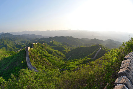 Majestic sunrise over the great wall of china amidst lush greenery and rolling hills beyondの写真素材