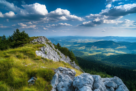 Breathtaking mountain view rocky outcrop overlooking lush valley and blue sky with cloudsの写真素材