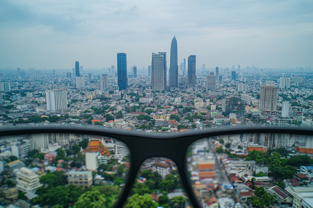 Close up of black glasses reflecting bangkok cityscape with a minimalist bokeh backgroundの写真素材