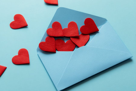 Flat lay photography of red hearts in an envelope on a blue background for romantic themesの写真素材