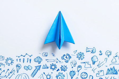 Minimalist image of a blue paper airplane with creative business doodles on a white backgroundの写真素材