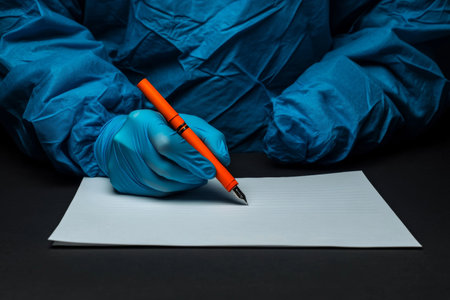 Close up of doctor in blue robe and gloves writing on notepadの写真素材