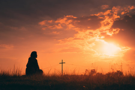Silhouette of a woman sitting on grass by a cross at sunset a reflection on faith and lifestyle