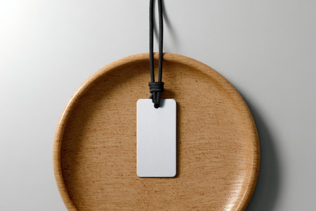 Elegant mockup of a white rectangular tag on a round plate against a neutral backgroundの写真素材