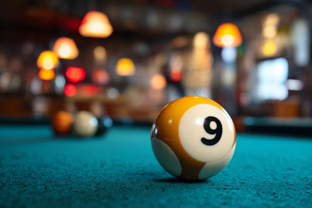 Close up of billiard ball number 9 on table with a blurred background of a vibrant pool hallの写真素材