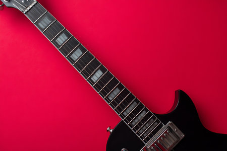Black electric guitar on red background ideal for rock music themes and creative copy spaceの写真素材