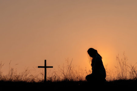 Silhouette of a woman praying by a cross at sunset a hopeful scene of faith and reflection