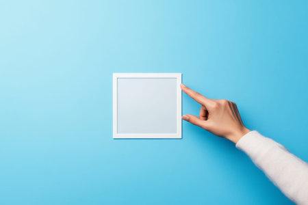 Hand interacting with a white modern screen featuring a square button against a blue background