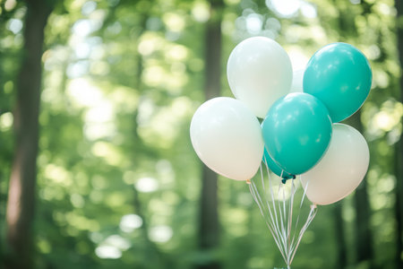 Teal and white balloons tied together in a serene forest with soft focus and natural lightingの写真素材