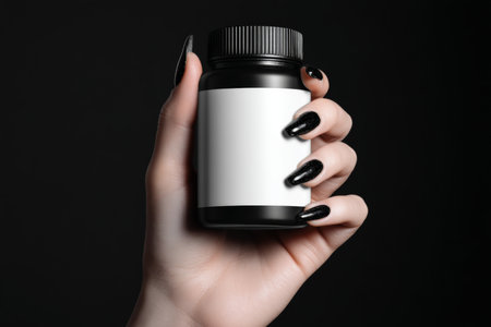Photorealistic black and white image of hand with painted nails holding empty supplement bottleの写真素材