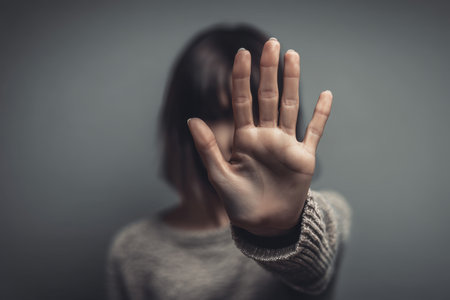 Woman gesturing a stop sign with her palm against gray background expressing fear and concernの写真素材