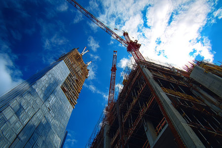 Construction scene featuring a crane overlooking a building project beneath a clear blue skyの写真素材