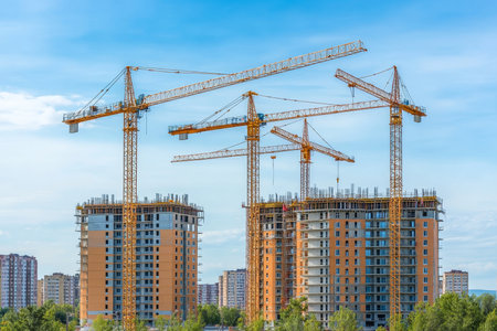 Construction site photography cranes and multi storey buildings against a clear blue skyの写真素材