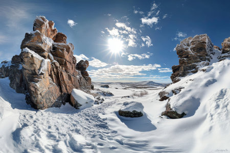 Stunning panoramic view of a snowy landscape with rocky formations beneath a bright sunlit sky