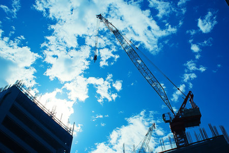 Construction site featuring crane and building under a clear blue sky in urban environmentの写真素材