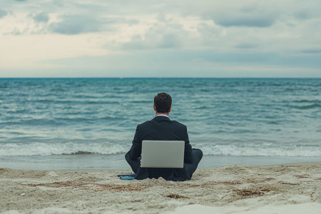 Businessman working on laptop at beach embracing work life balance without days offの写真素材