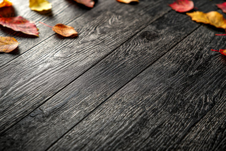 Textured dark wood surfaces adorned with colorful fall foliage, evoking warm, cozy moods suitable...