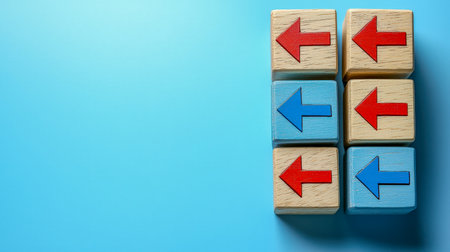 Six natural wooden cubes feature vibrant red and blue arrows diverging in opposite directions, set against a soothing pastel blue backdrop, highlightiの写真素材