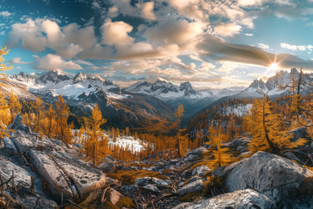 Autumnal mountain landscape with golden larch trees and snow dusted peaks in panoramic viewの写真素材