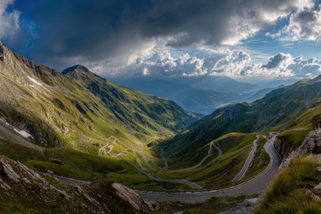 A serpentine road weaving through vibrant foliage in a valley framed by moody, cloud-laden skies,...