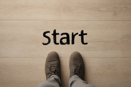 A pair of footwear poised on textured wooden planks beneath a motivating 'start' message, evoking fresh beginnings and new journeys.の写真素材