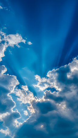 Gentle rays of sunlight pierce through scattered clouds, illuminating a serene sky and creating a peaceful, uplifting atmosphere.の写真素材