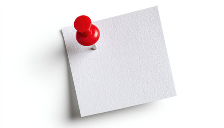 A pristine white paper serves as a blank canvas, secured by a vibrant red pin on a seamless white background, evoking focus and clarity for remindersの写真素材