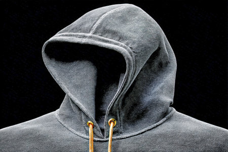 A textured close-up reveals the soft fabric and sleek design of a deep gray hoodie, with drawstrings...