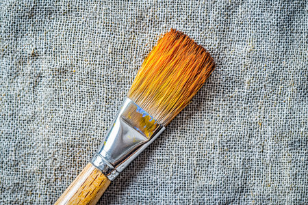 An artist's brush rests atop a rough, woven fabric, highlighting tactile details and inspiring creativity for craftsmanship or textile design projectsの写真素材