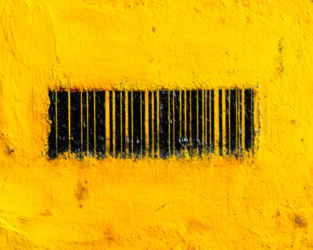 A bold black barcode etched onto a vibrant yellow wall, creating a striking contrast that highlights urban street art and modern design elements.のeditorial素材