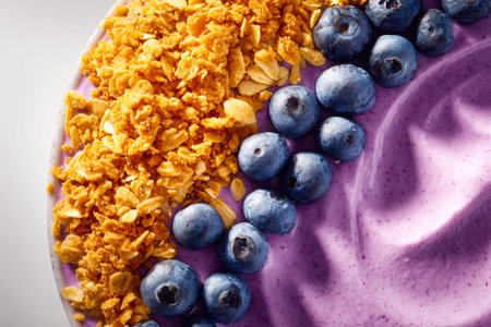 A colorful bowl of creamy blueberry yogurt topped with toasted granola, evoking freshness and...