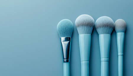 An elegant collection of five slender blue cosmetic brushes, meticulously aligned on a pastel-hued...
