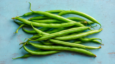 Vibrant green beans scattered across a rustic blue wooden background, evoking freshness and natural simplicity for culinary or market themes.の写真素材