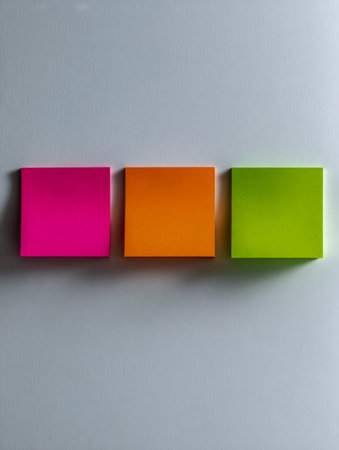 Three lively, square-shaped notes in pink, orange, and green are precisely arranged on a neutral...