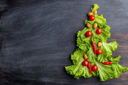 An artful display of vibrant vegetables crafted into a holiday-themed shape, set against a rich, dark wooden background.の写真素材