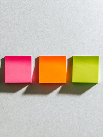A lively assortment of neon pink, vivid orange, and fresh green notes lined up against a textured white surface, embodying energetic planning and vibrant ideas.の写真素材