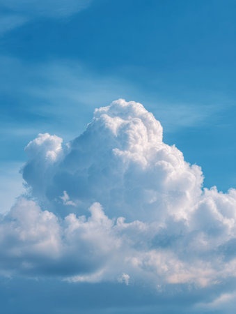 A tranquil sky scene featuring soft, billowing white clouds set against a vibrant blue backdrop,...