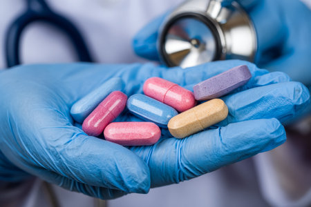 A healthcare worker's hand displays an assortment of vibrant capsules and tablets, with a...