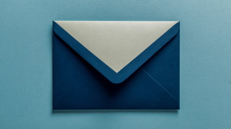 A sophisticated dark blue envelope featuring a crisp white flap rests on a gentle light blue...
