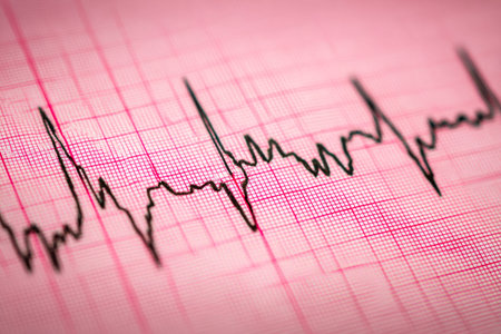 A close-up of a medical device showing a pulsating heart rate graph on a sheet, conveying a sense of...