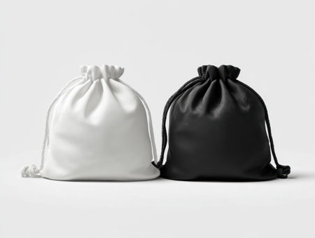 Two minimalist fabric pouches in sleek black and white, positioned parallel on a clean backdrop, evoking elegance and versatility with gentle illumination.の写真素材