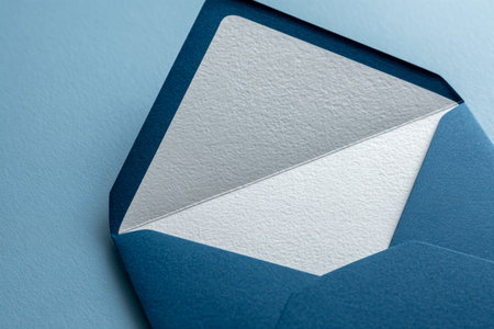 A vibrant blue envelope with a subtly textured white sheet peeking out, set against a matching blue backdrop, ideal for elegant invites or personal messages.の写真素材