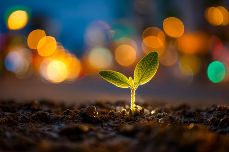 A tiny sprout emerges from dark earth beneath a glowing urban skyline, symbolizing growth and hope amid energetic city life.の写真素材