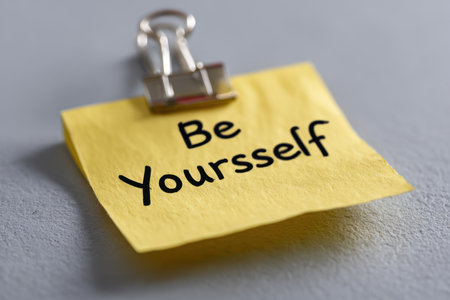 A handwritten affirmation emphasizing authenticity is secured by a sleek metal clip against a textured, earthy-toned backdrop, inspiring confidence and personal growth.の写真素材