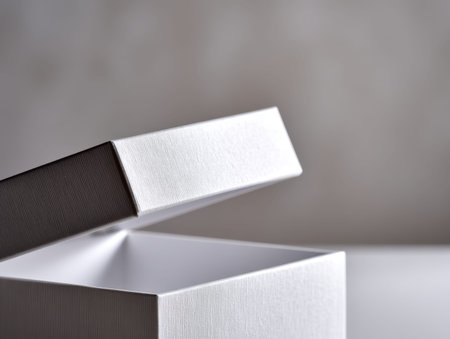 A pristine white box with a subtle textured finish, gently ajar to reveal its empty interior, set...