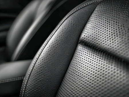 A close-up of sleek black leather with intricate perforations and precise stitching, highlighting...